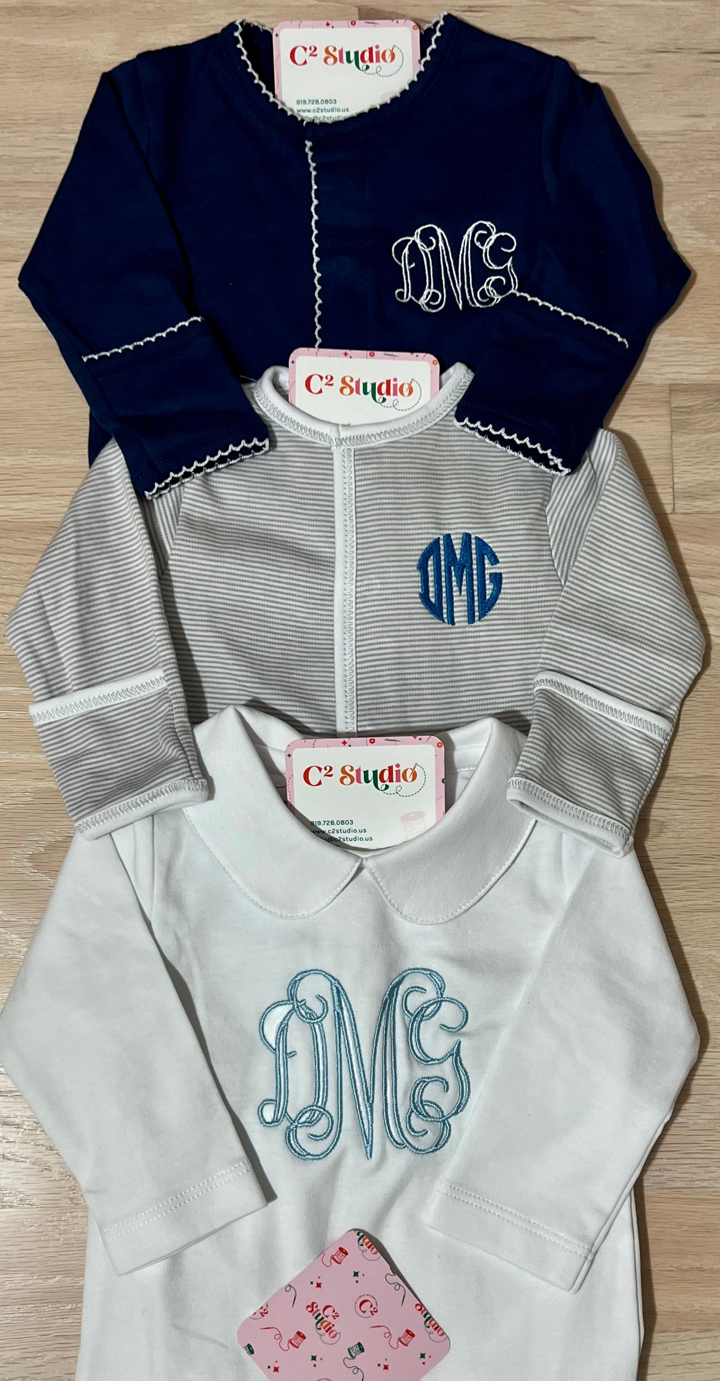 A set of three pieces of baby sweaters with embroidered monograms. They come in navy blue, gray, and white colors.