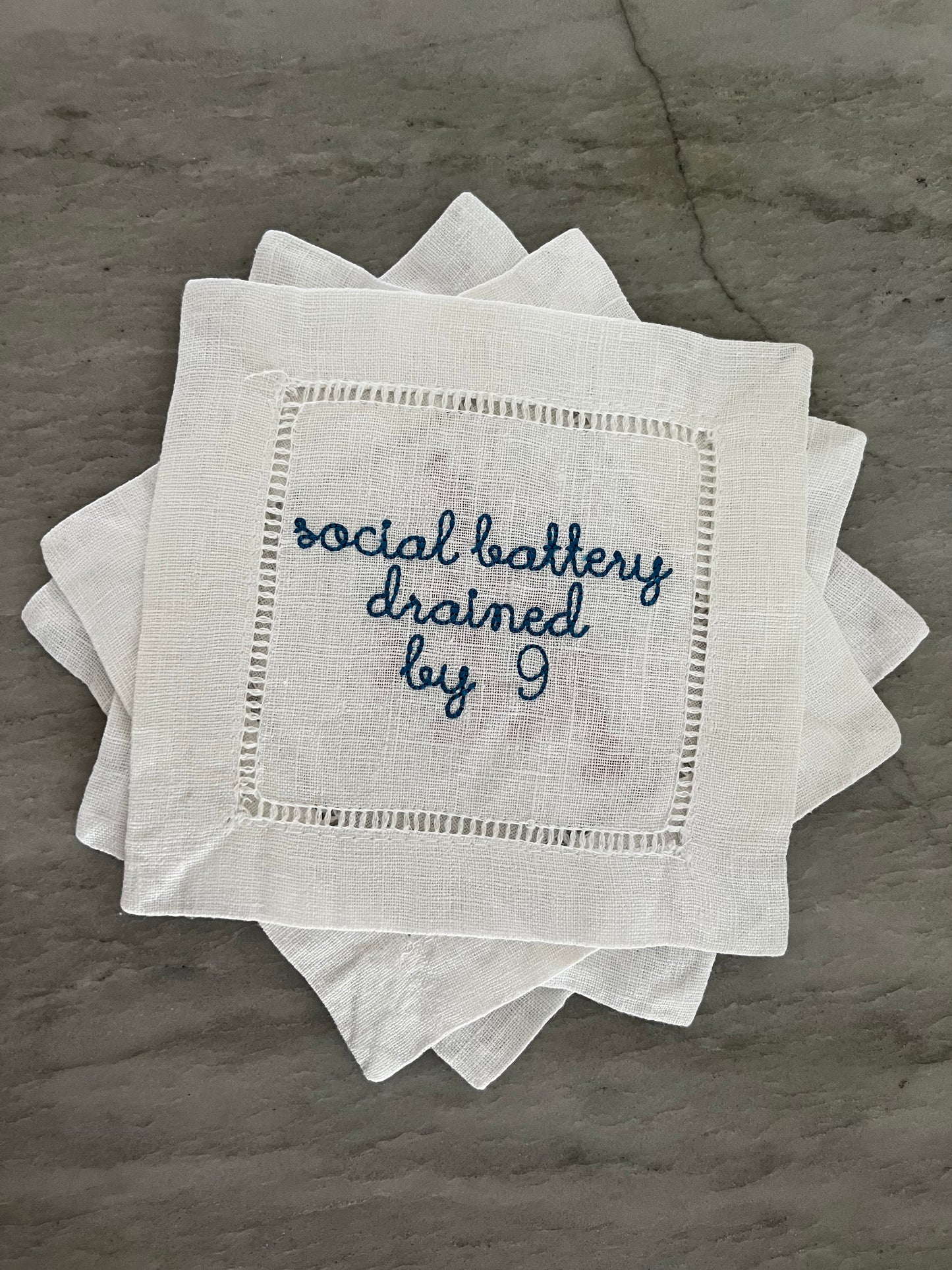 100% Linen Hemstitched Cocktail Napkin with embroidered 'Social Battery Drained by 9' in blue text