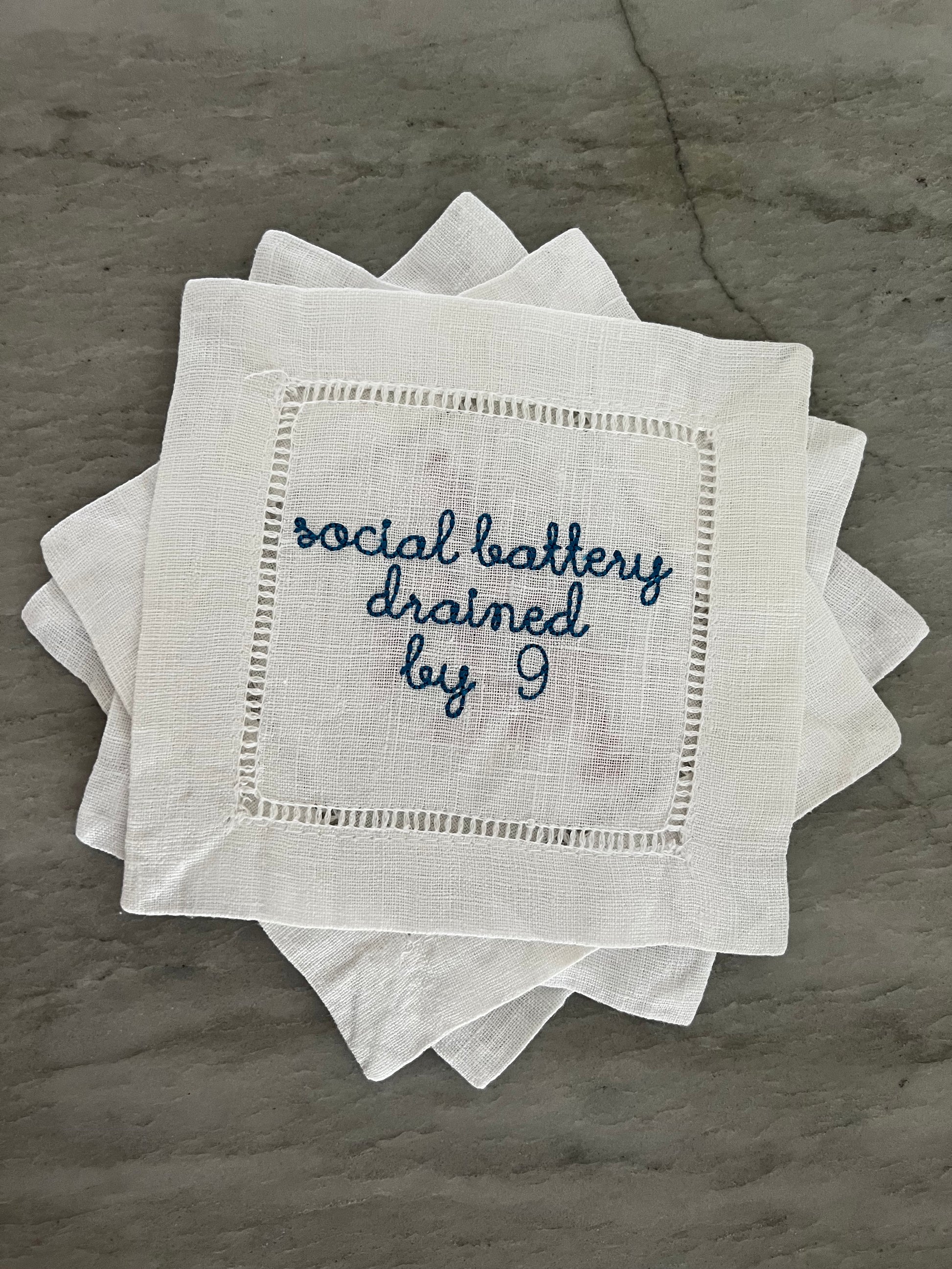 100% Linen Hemstitched Cocktail Napkin with embroidered 'Social Battery Drained by 9' in blue text