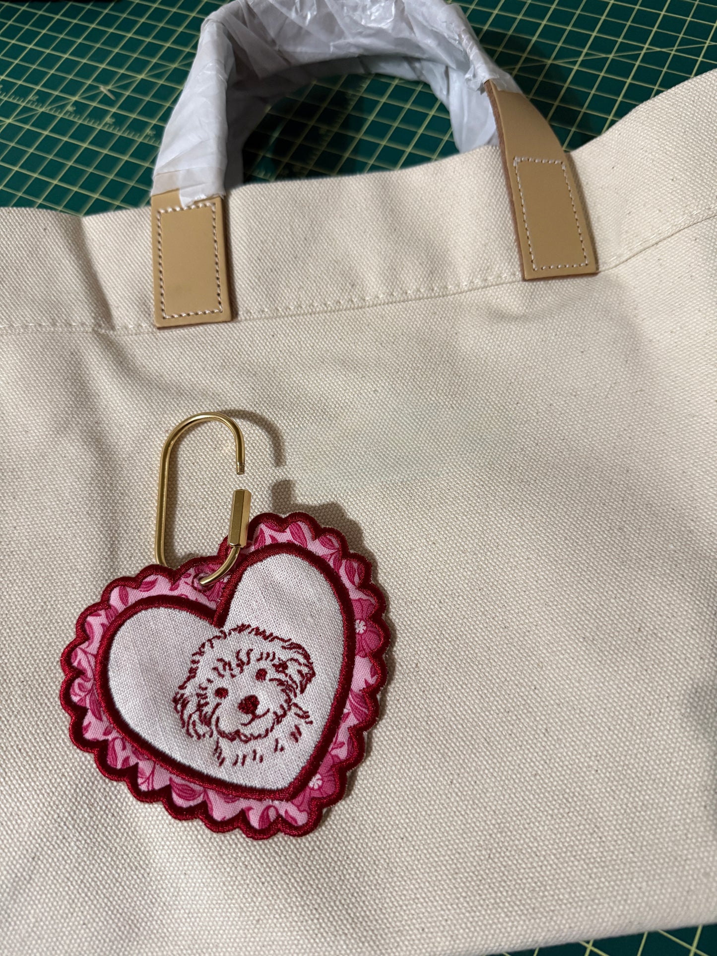 Beige tote bag with an embroidered heart-shaped keychain charm with a dog portrait