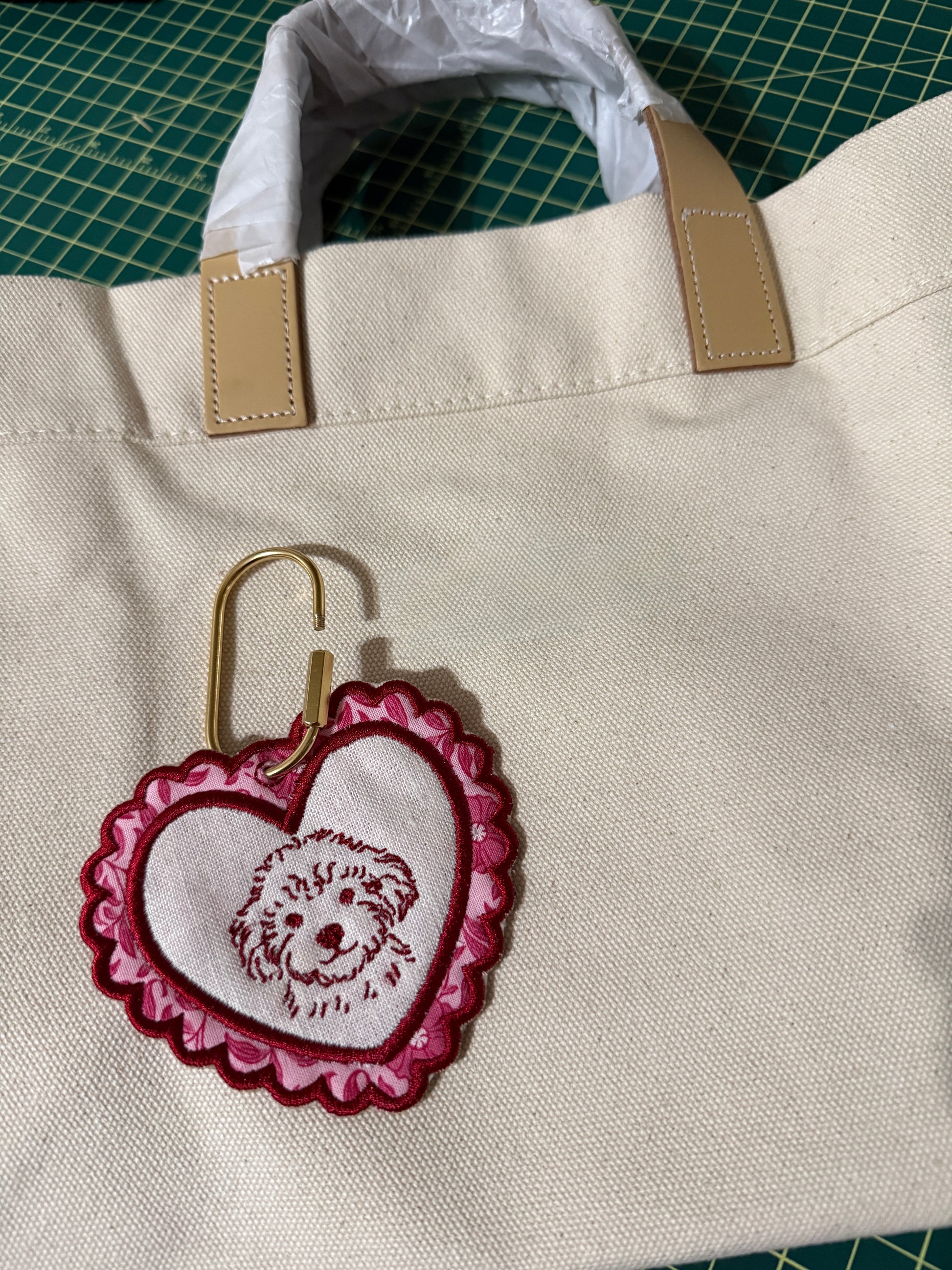 Beige tote bag with an embroidered heart-shaped keychain charm with a dog portrait