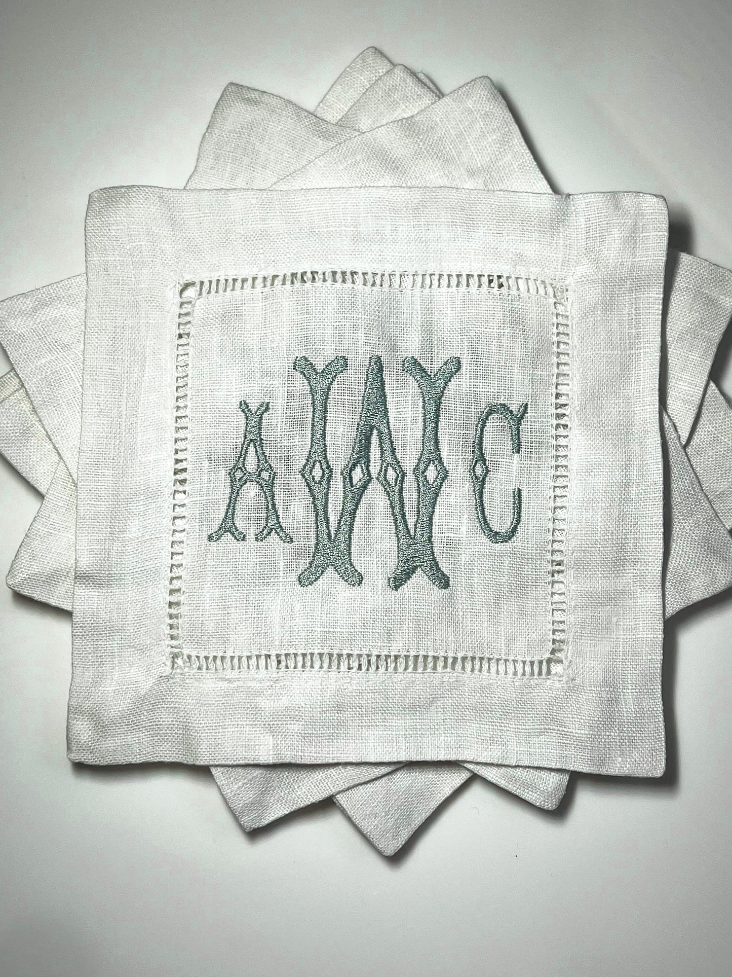 A set of monogrammed, hemstitched linen cocktail napkins with embroidered initials 'AWC'