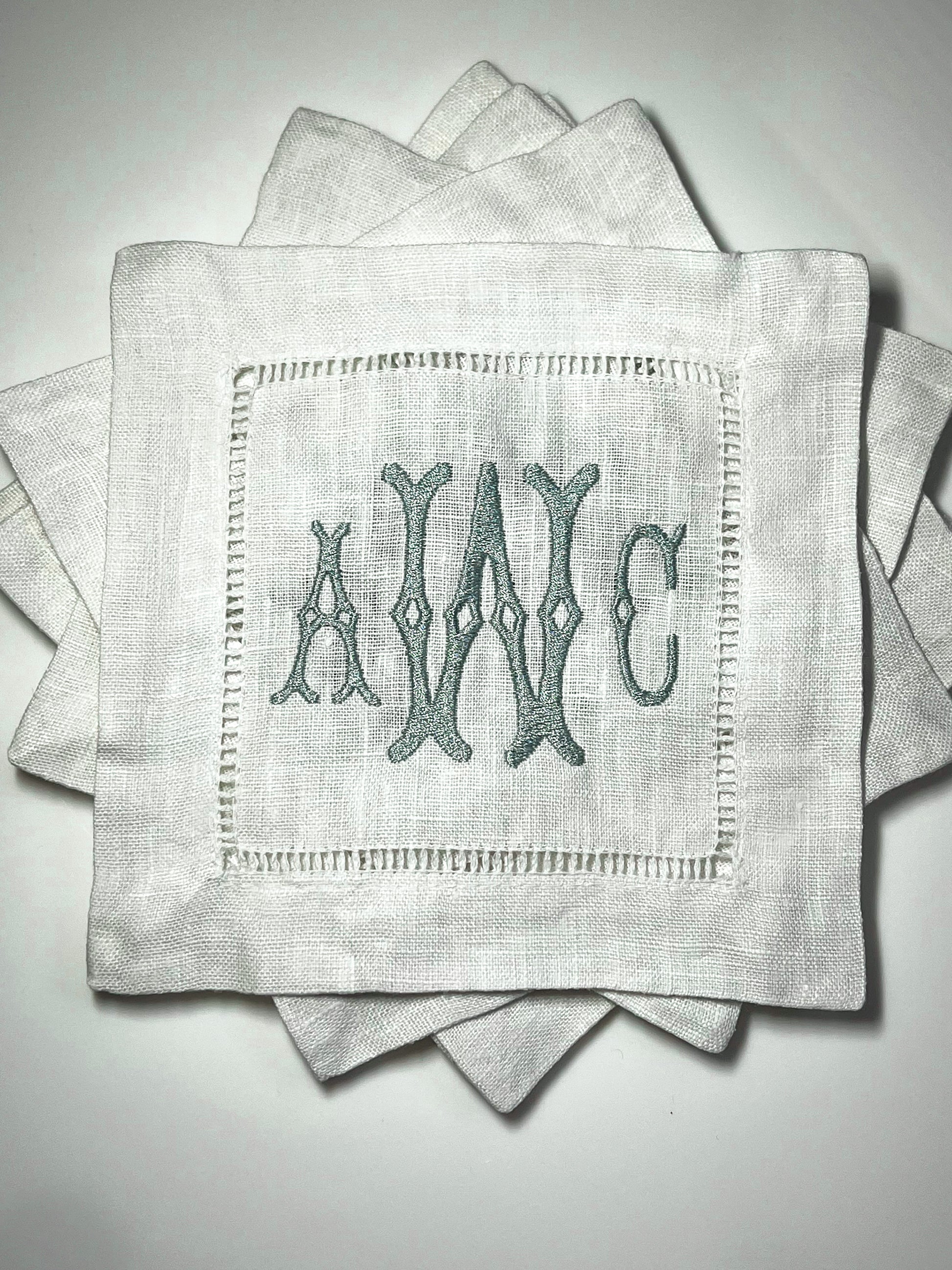 A set of monogrammed, hemstitched linen cocktail napkins with embroidered initials 'AWC'