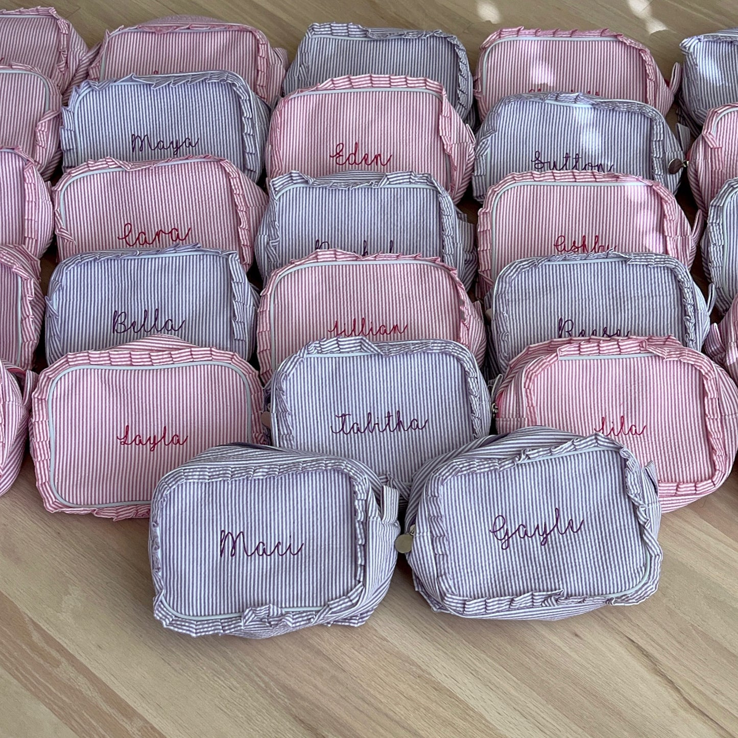 A collection of red and blue personalized makeup bags with embroidered monograms