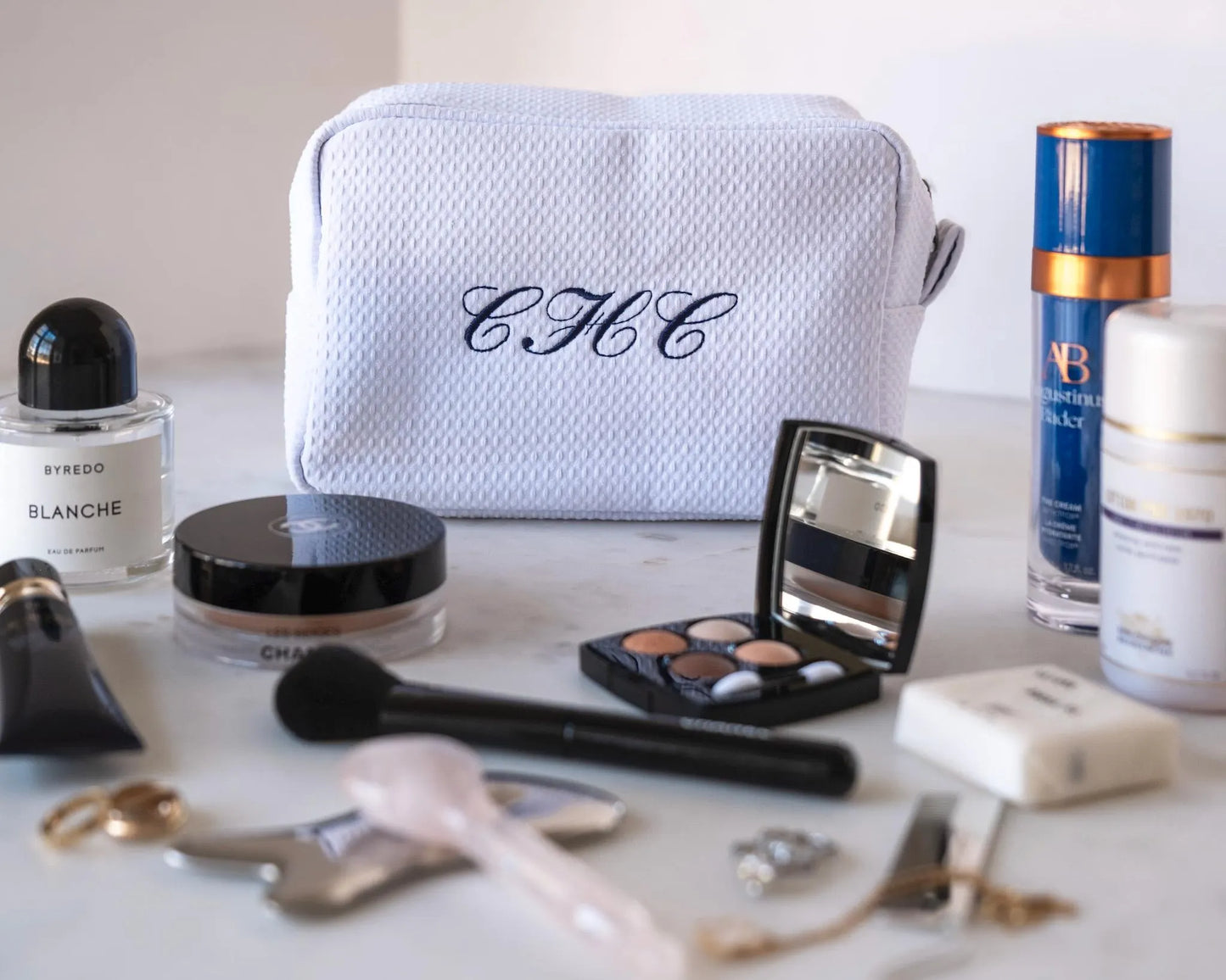 Personalized Waffle Makeup Bag with  an embroidered 'CHC' monogram surrounded by makeup products on a table.
