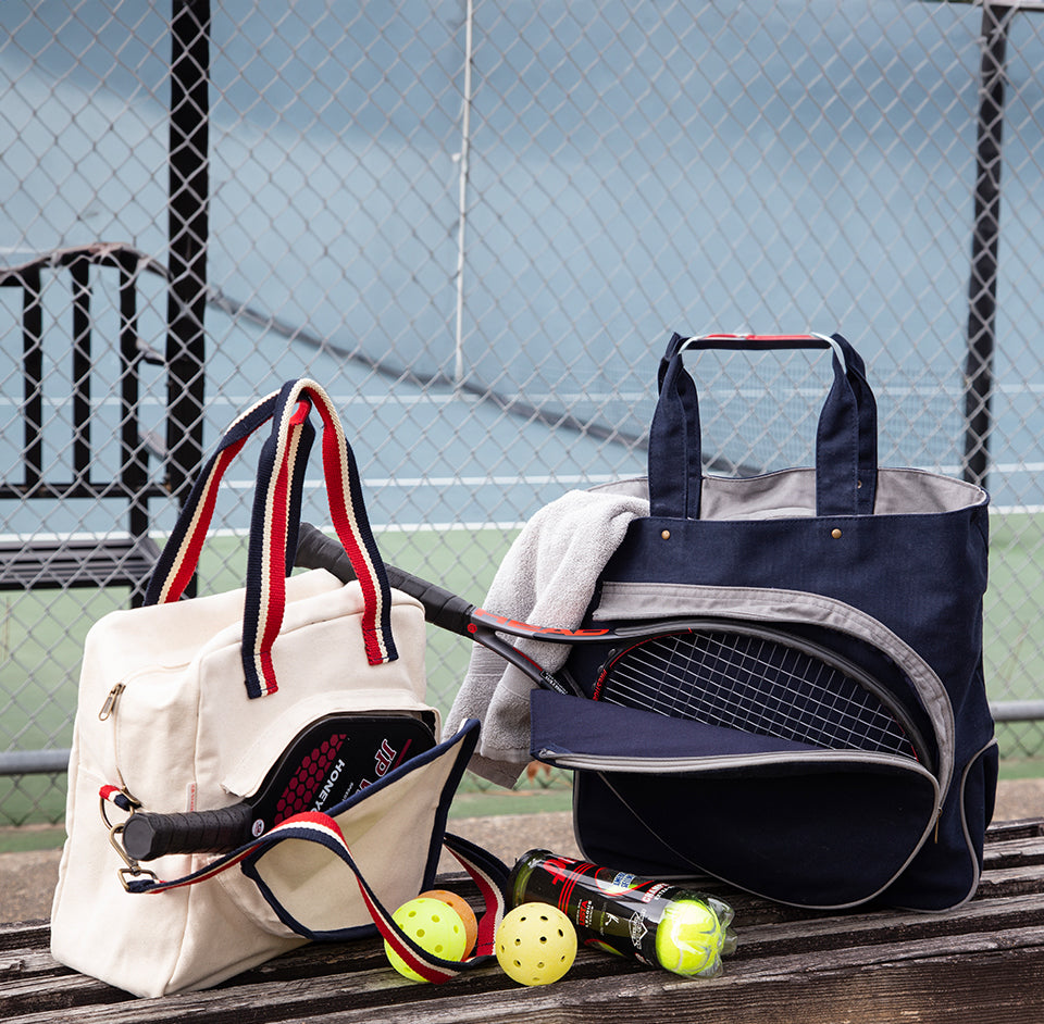 White and navy blue pickleball bags placed on a court bench
