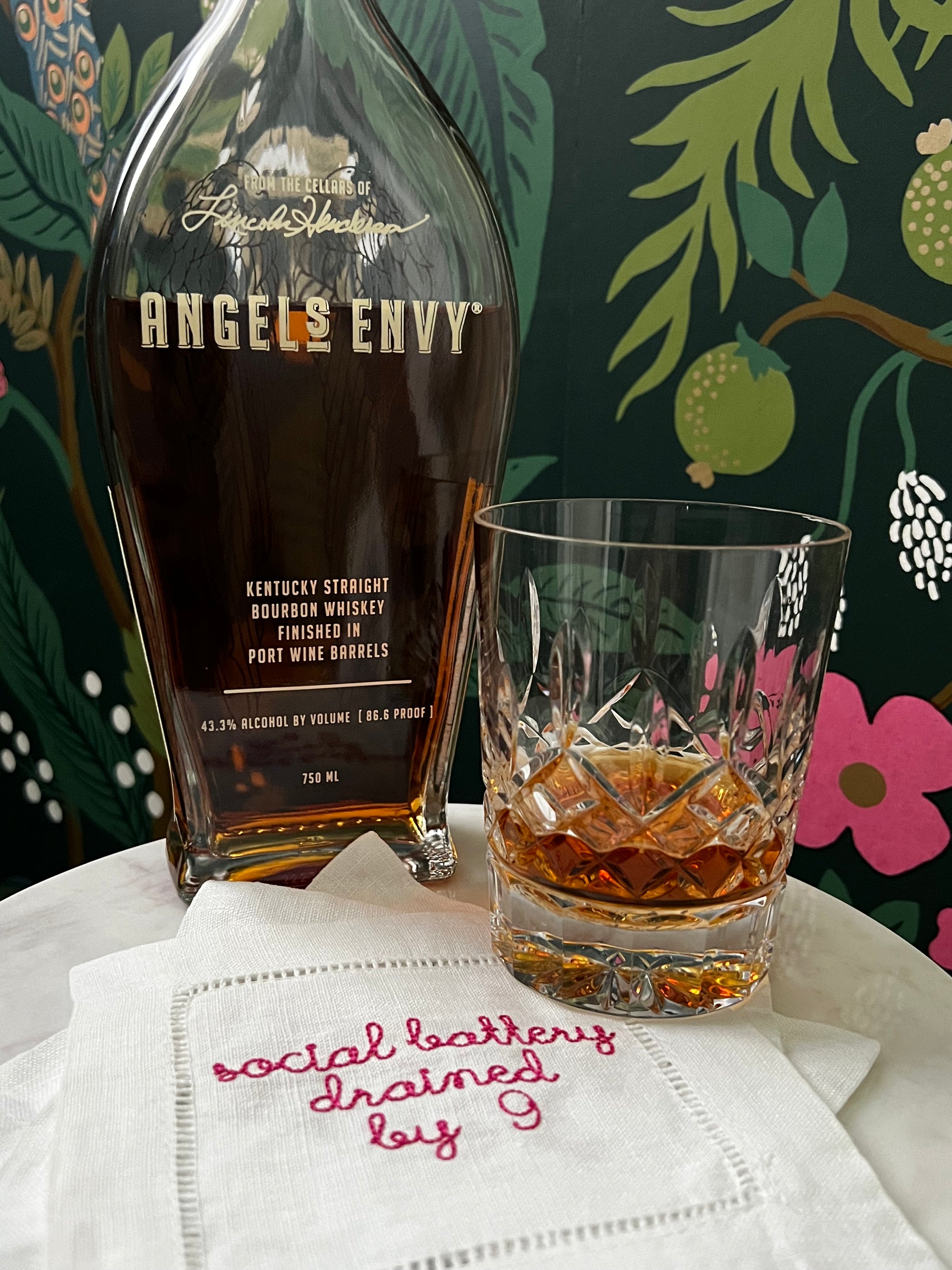Linen Hemstitched Cocktail Napkin with embroidered 'Social Battery Drained by 9' in red text, placed on a cocktail table