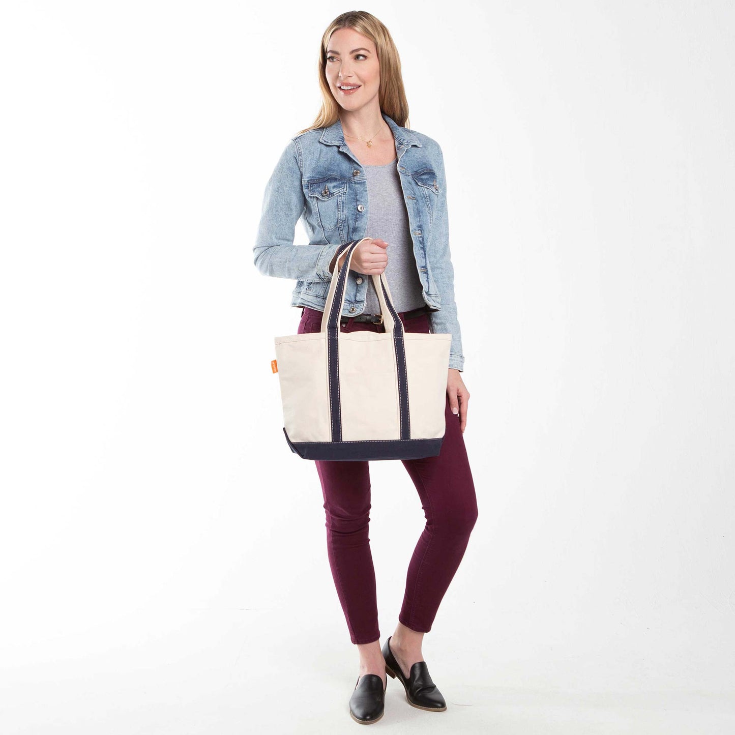 Model holding a beige and navy blue classic medium canvas tote