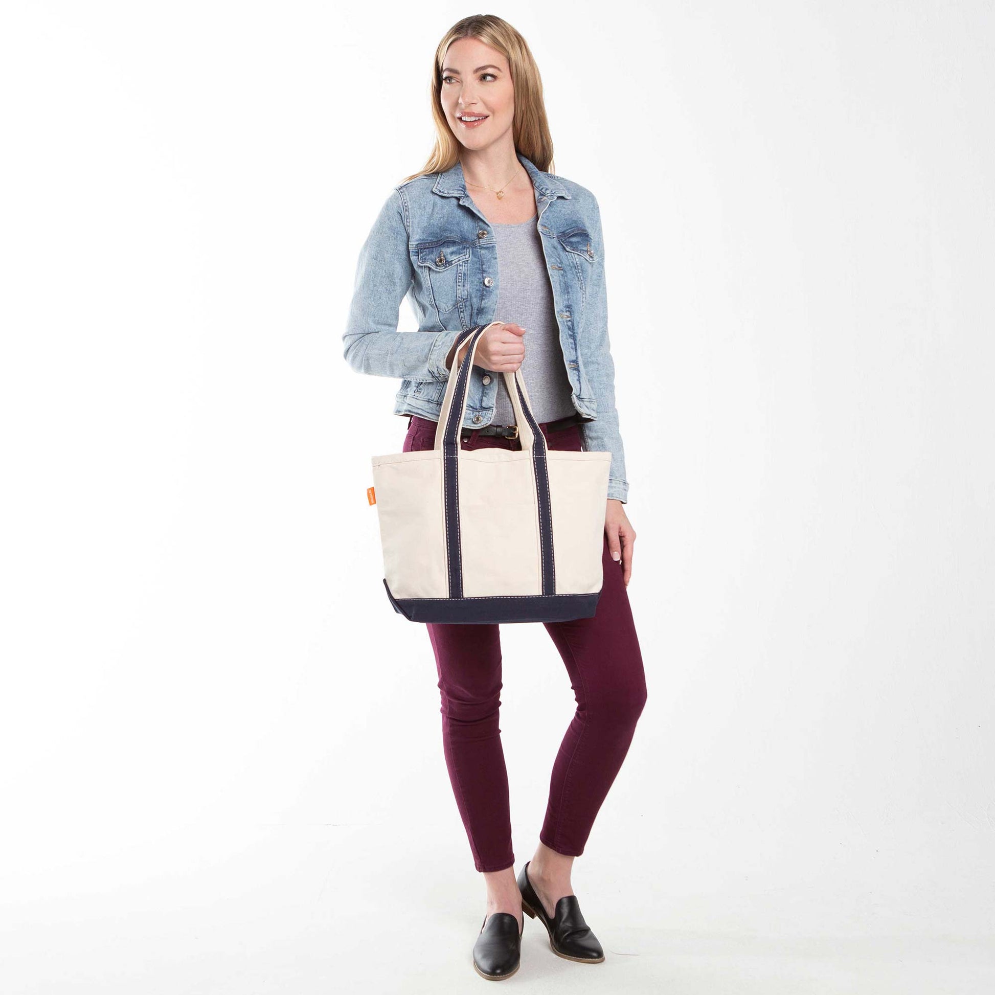 Model holding a beige and navy blue classic medium canvas tote
